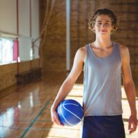 A athlete smiling at the camera and holding a basketball.