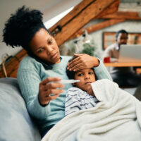 A woman taking care of her sick child who may have the flu or strep throat.