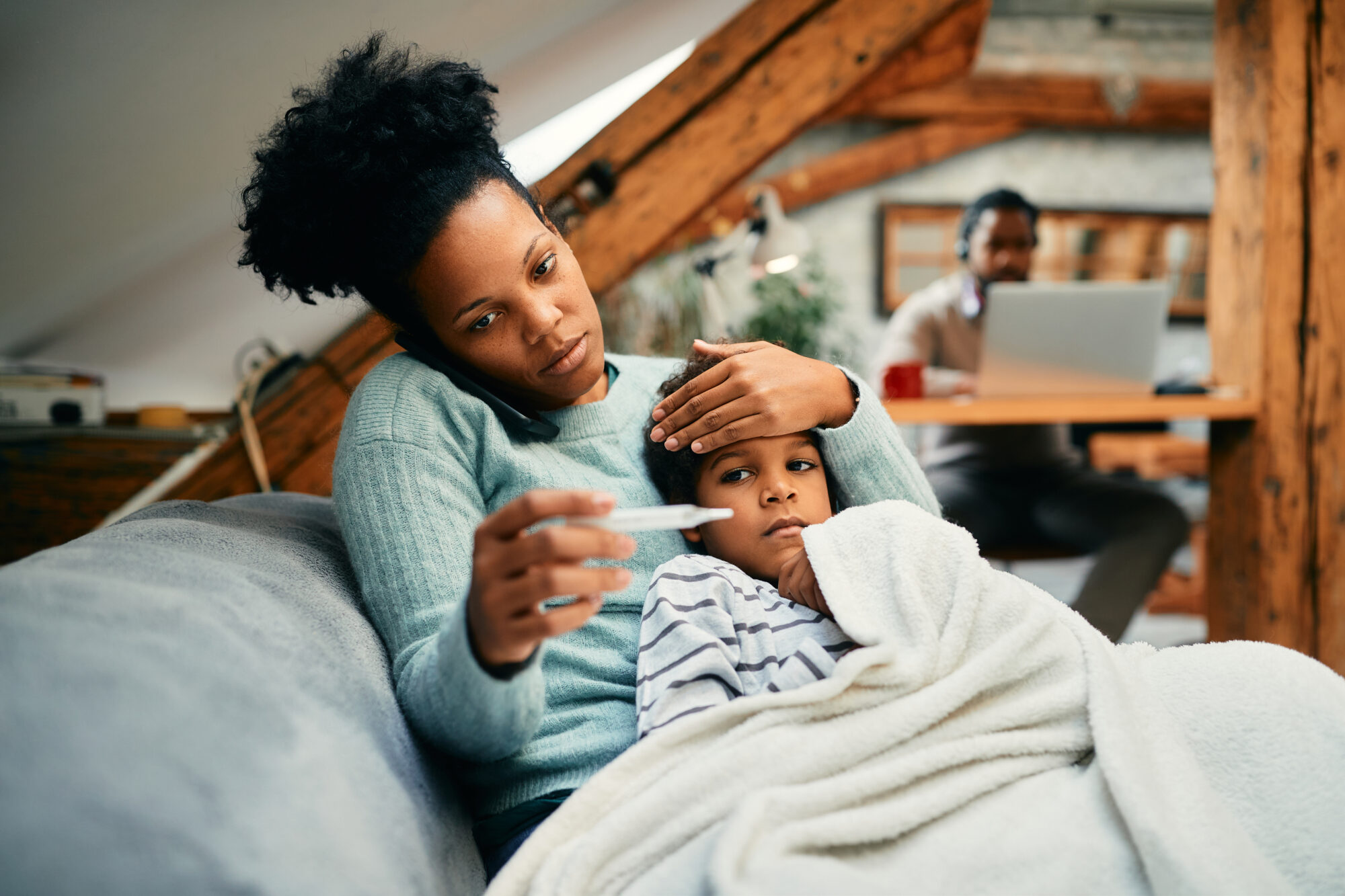 A woman taking care of her sick child who may have the flu or strep throat.