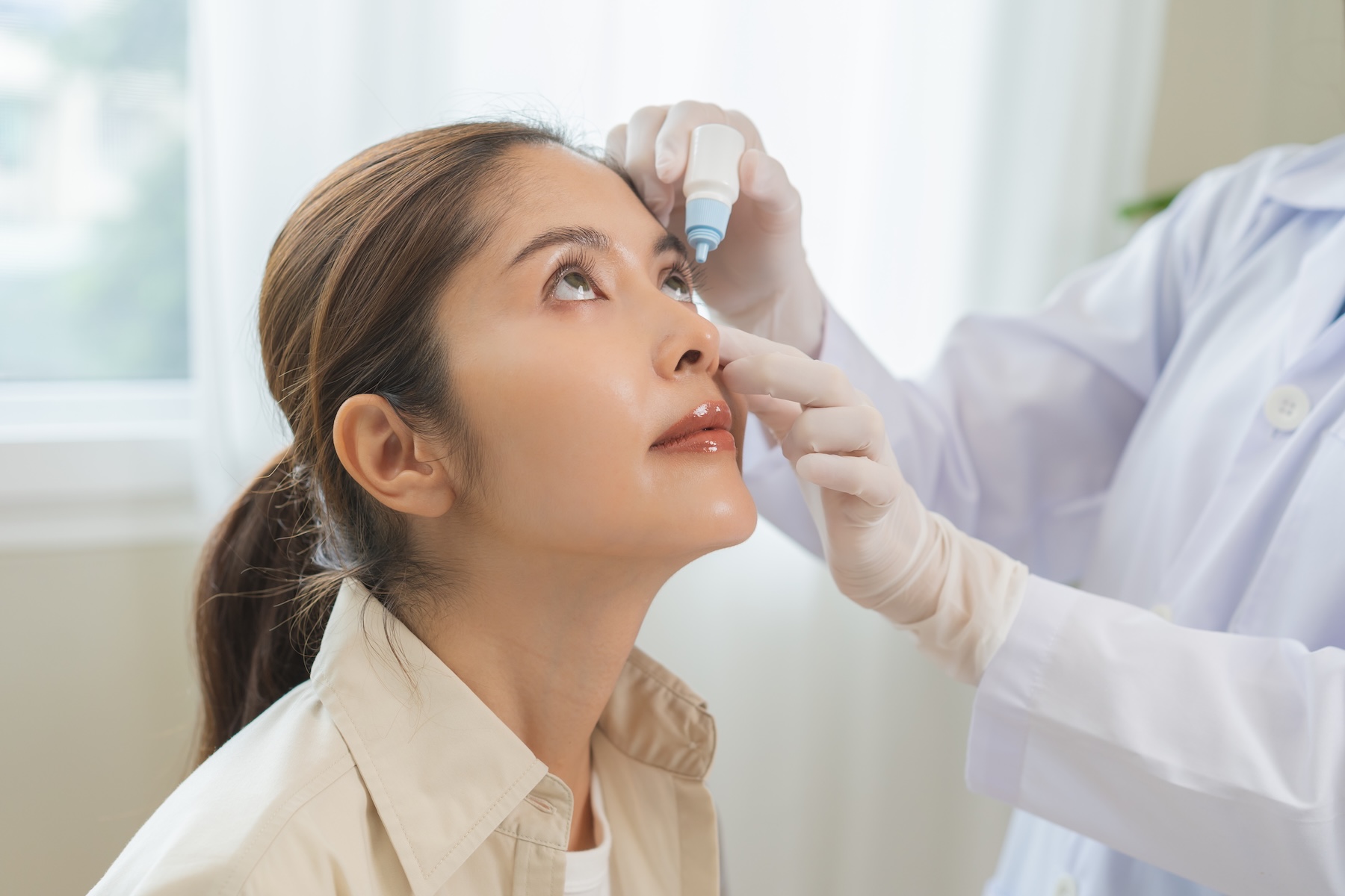 Doctor putting eyedrops in a woman's eyes